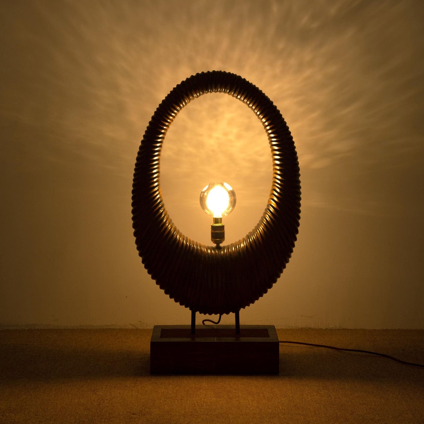 Decorative table lamp with a textured shade casting light on a wall.