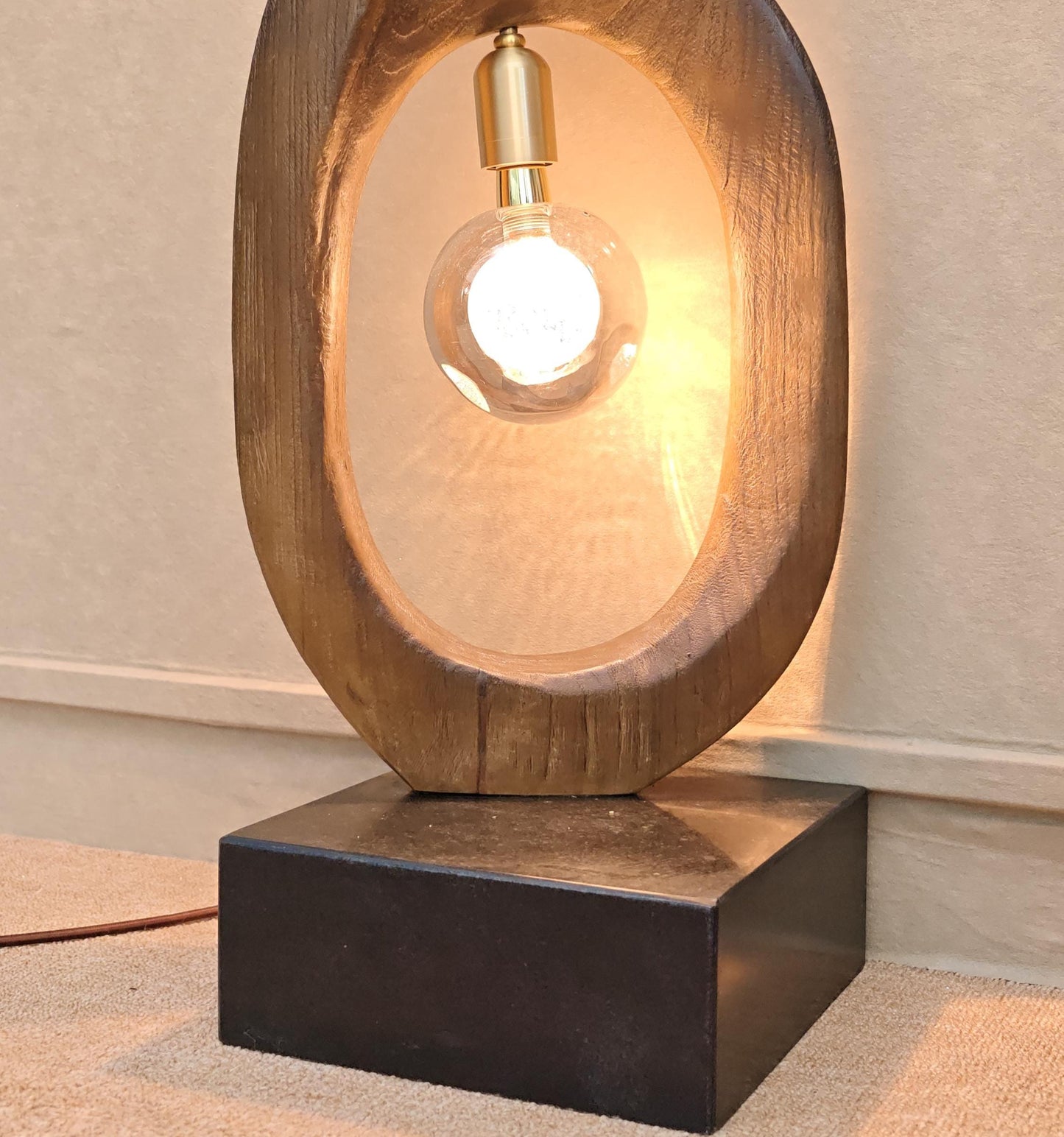 Wooden table lamp with a light bulb inside on a neutral background