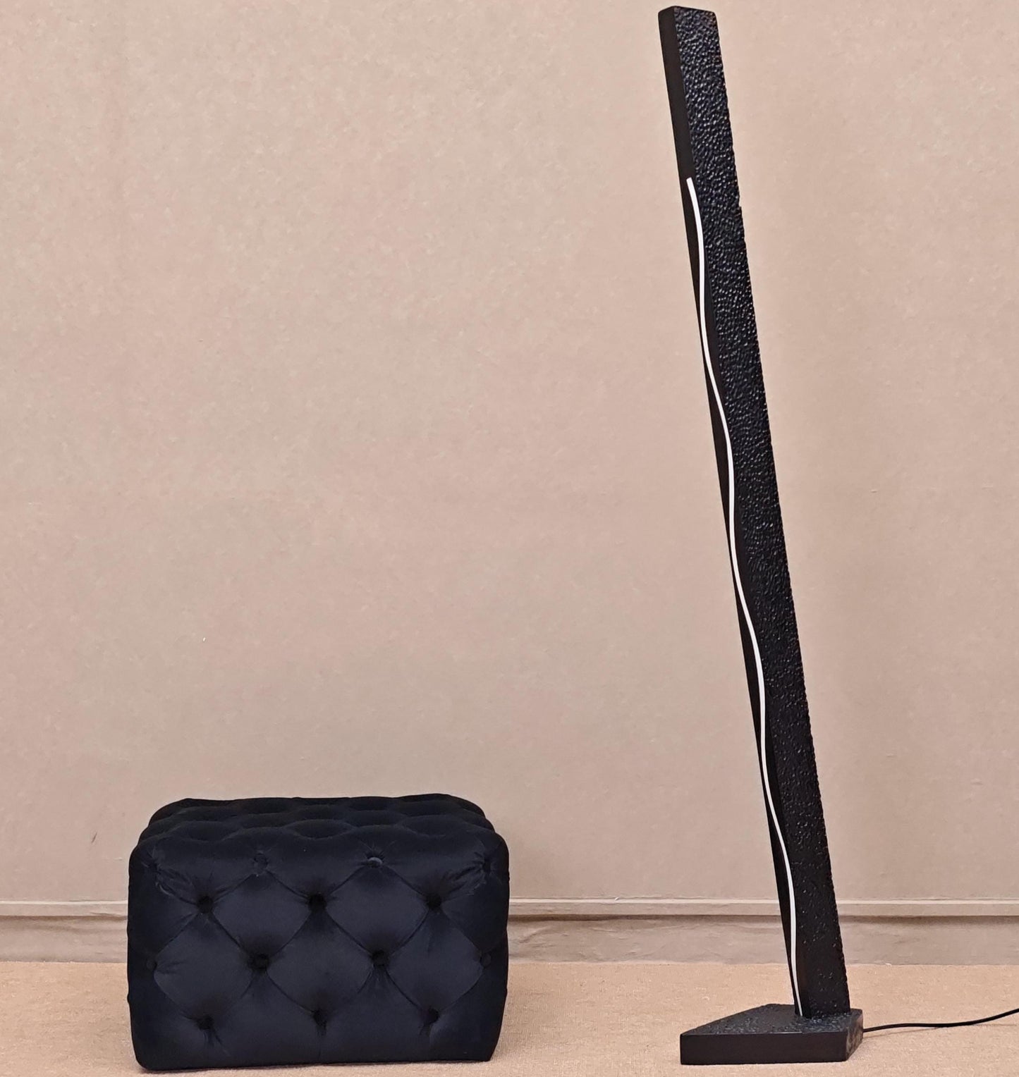 Black floor lamp and black ottoman on a beige background