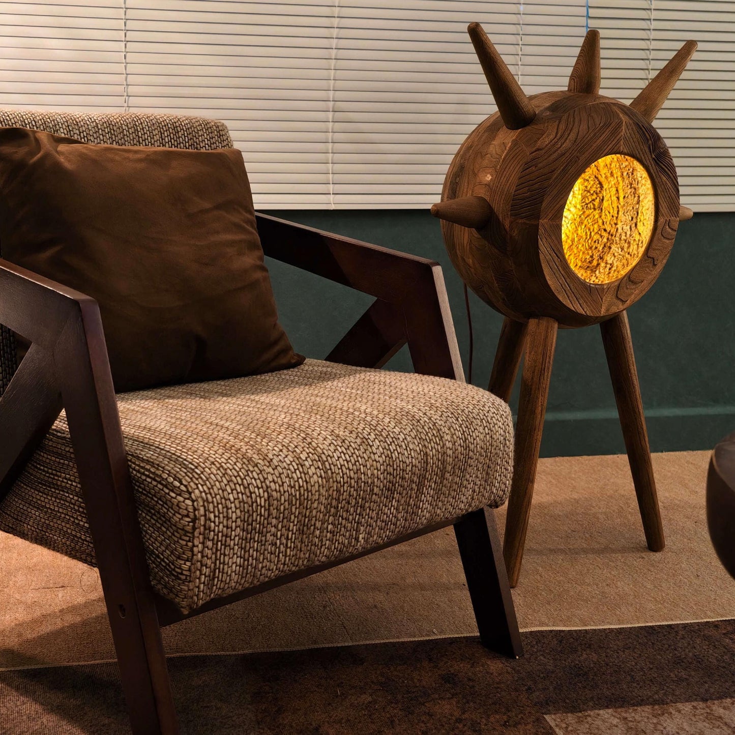 Wooden armchair with a textured cushion and decorative wooden lamp in a room setting.