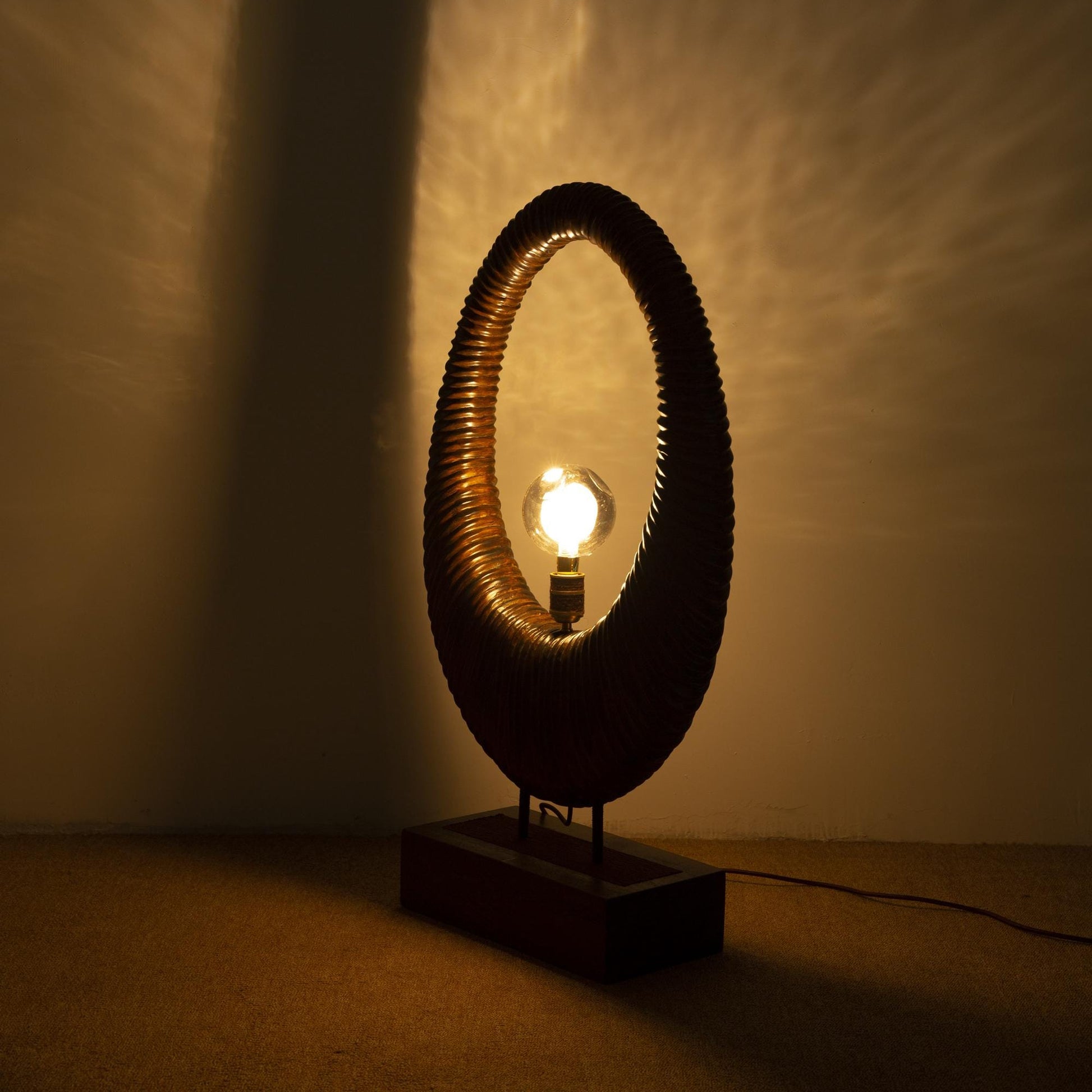 Decorative lamp with a circular design casting shadows on a wall.