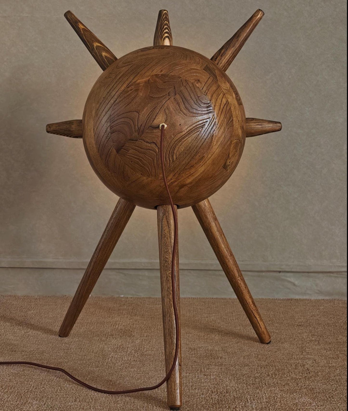 Wooden lamp with spiky top and tripod base on a neutral background