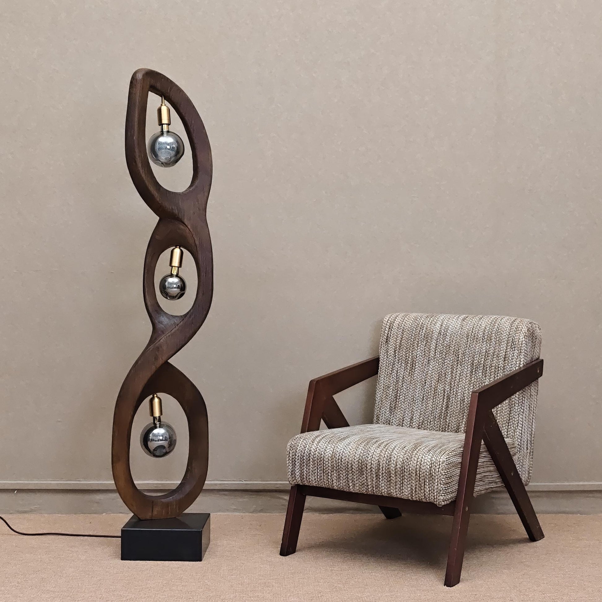 Modern floor lamp with spiral design next to a chair against a beige wall.