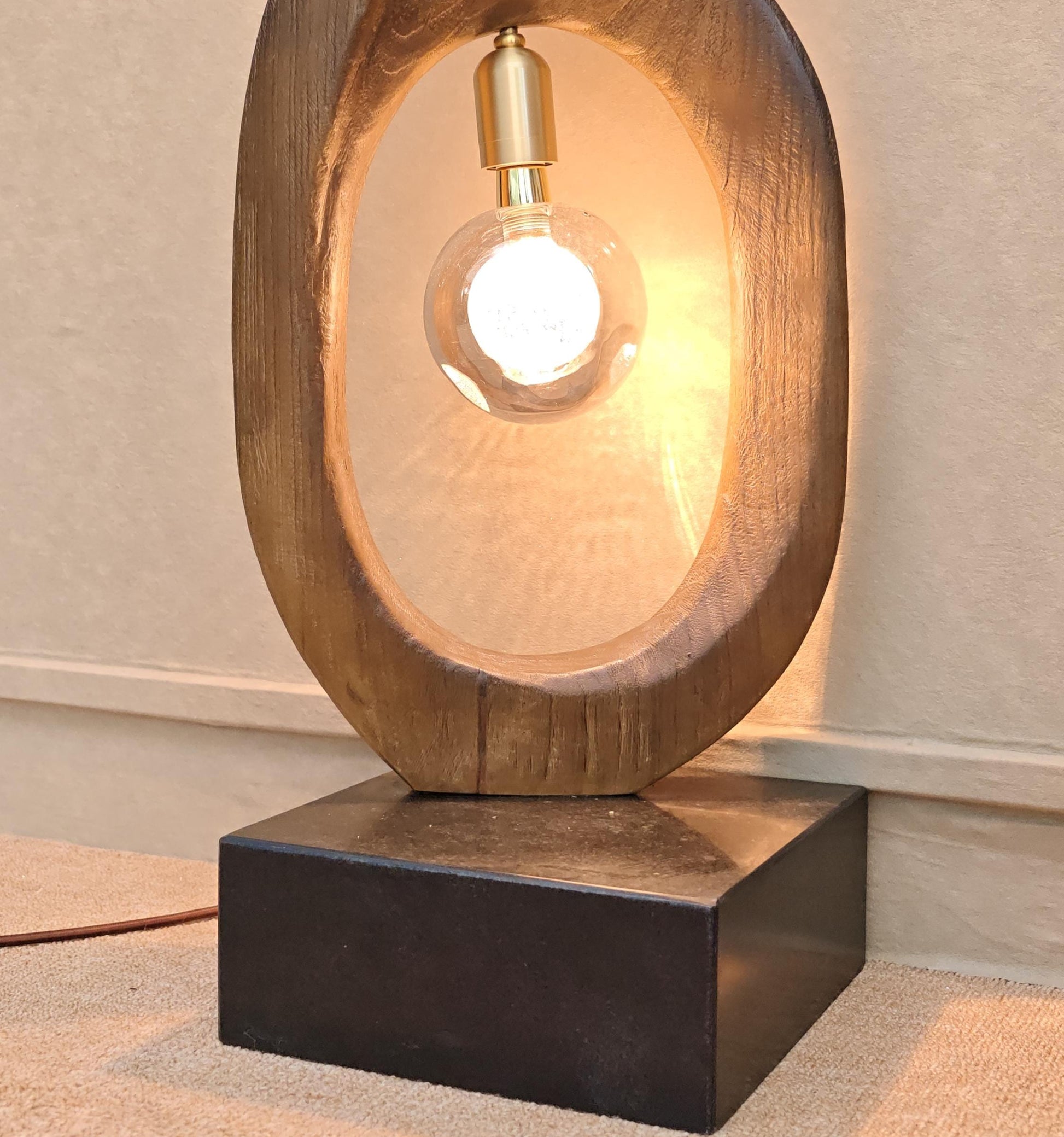 Wooden table lamp with a light bulb inside on a neutral background