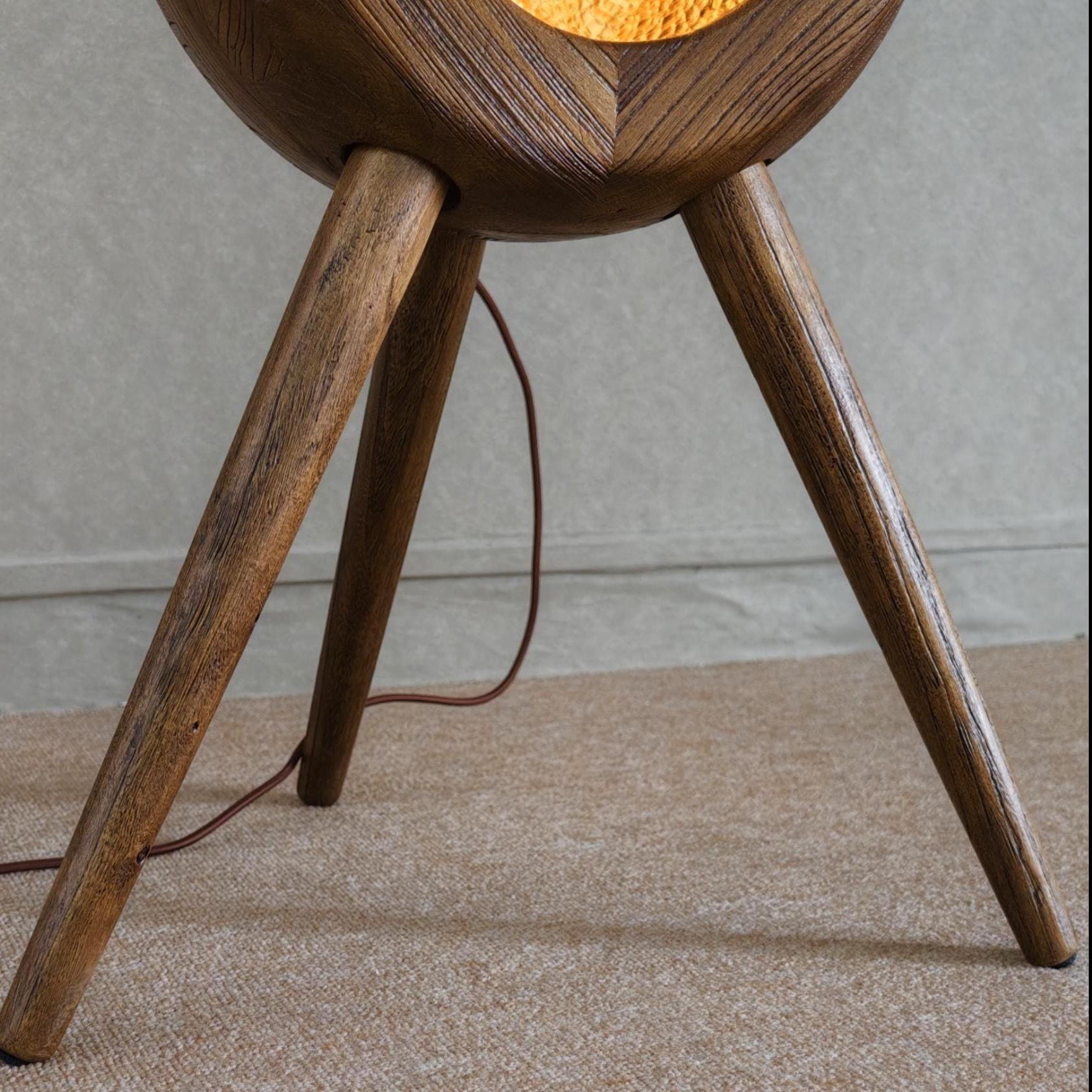 Wooden tripod lamp with a warm glow on a neutral background