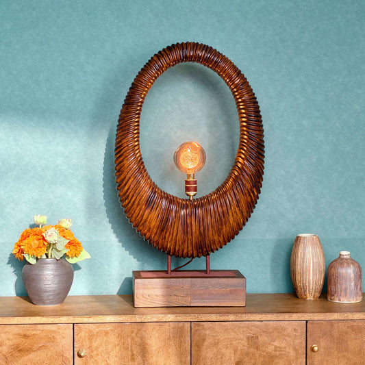Wooden sideboard with decorative lamp, vases, and flowers against a teal wall.