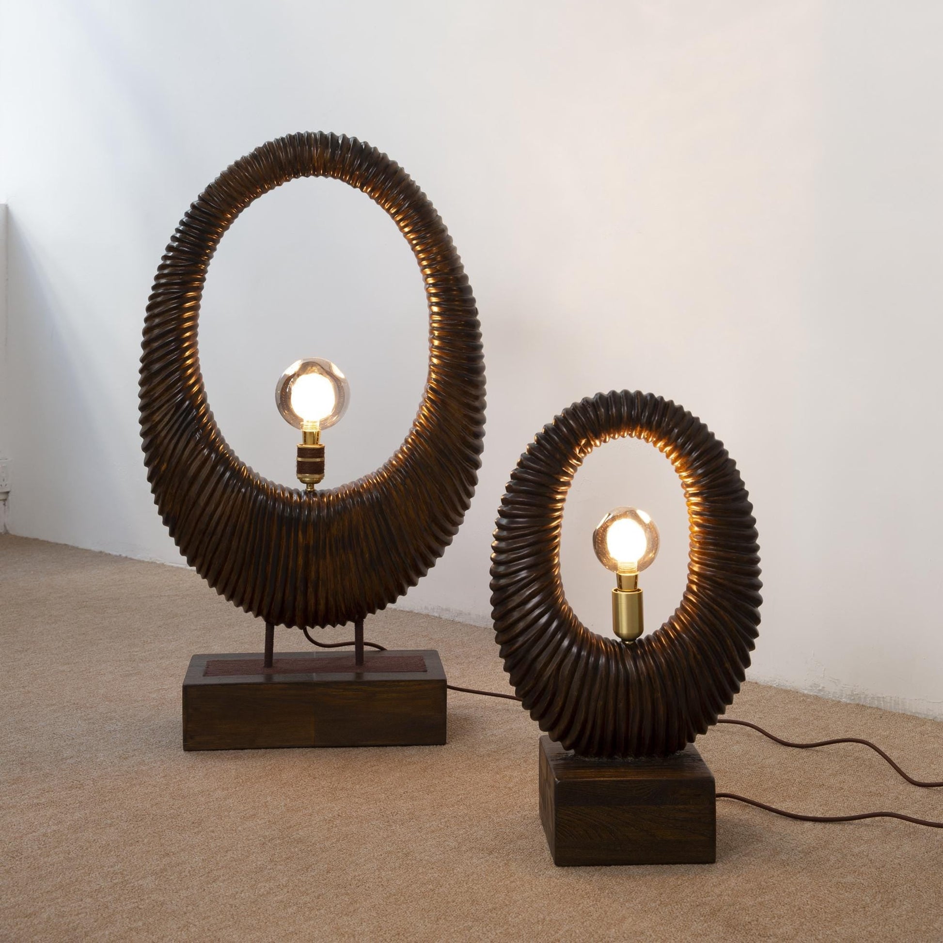 Two unique table lamps with circular designs on a plain background