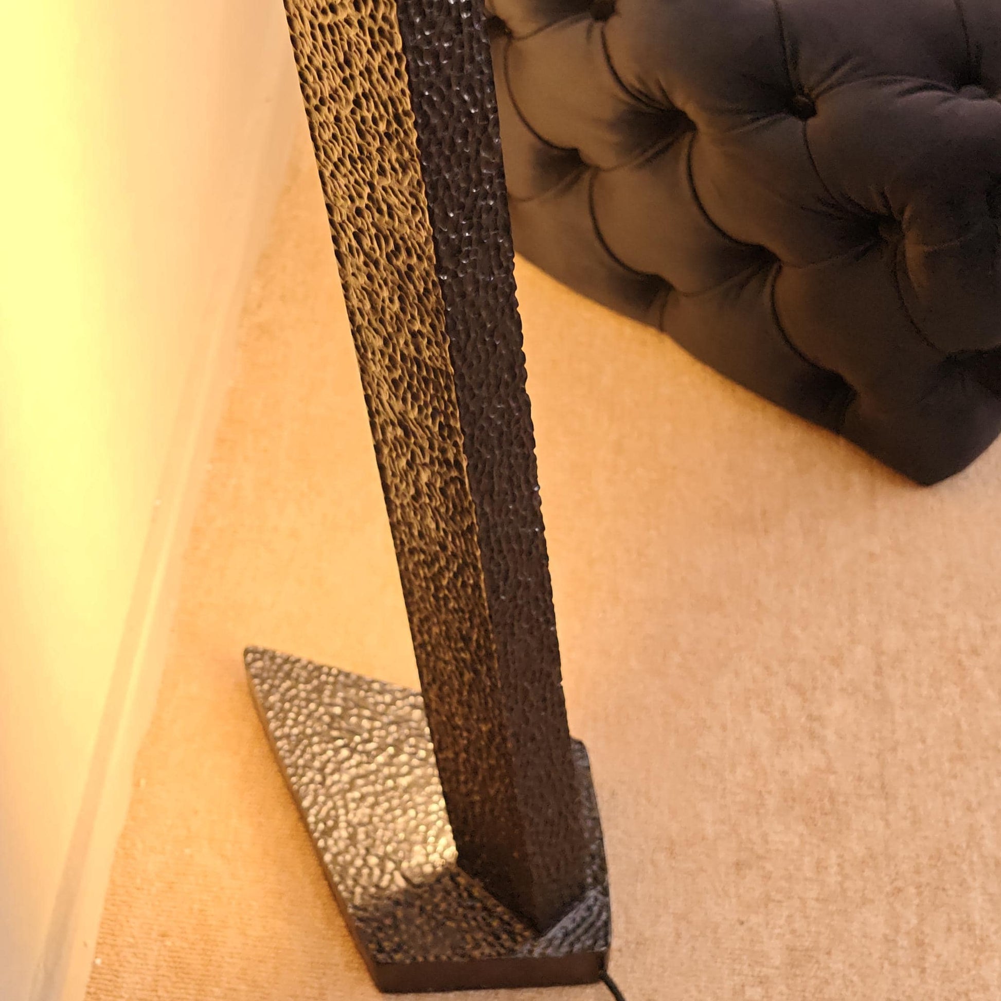 Decorative stand with textured surface and black base against a neutral wall.